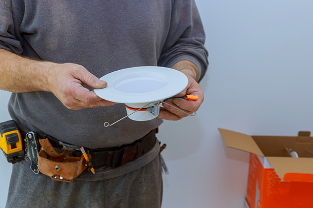 Elektro Kaufmann Mitarbeiter hat eine Lampe in der Hand.