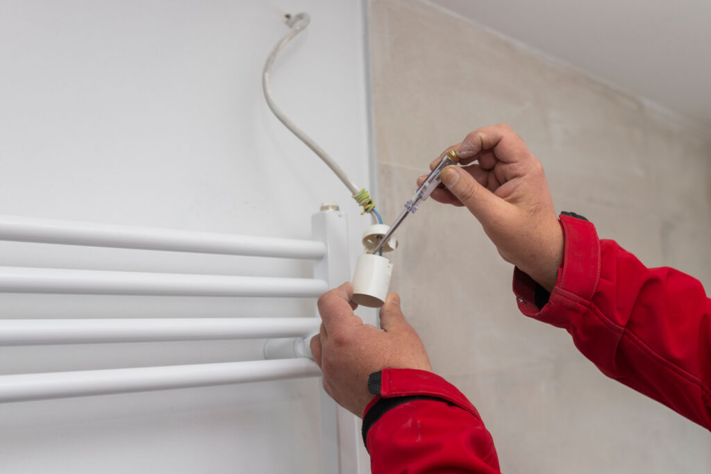 Mitarbeiter von Elektro Kaufmann, der eine Lampe an eine Badezimmerwand installiert.